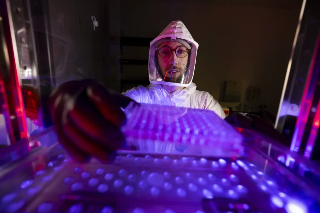 Graduate student Sean Ray pulls samples from an incubator as he simulates working in Stephen Tompkins lab at the Animal Health Research Center.