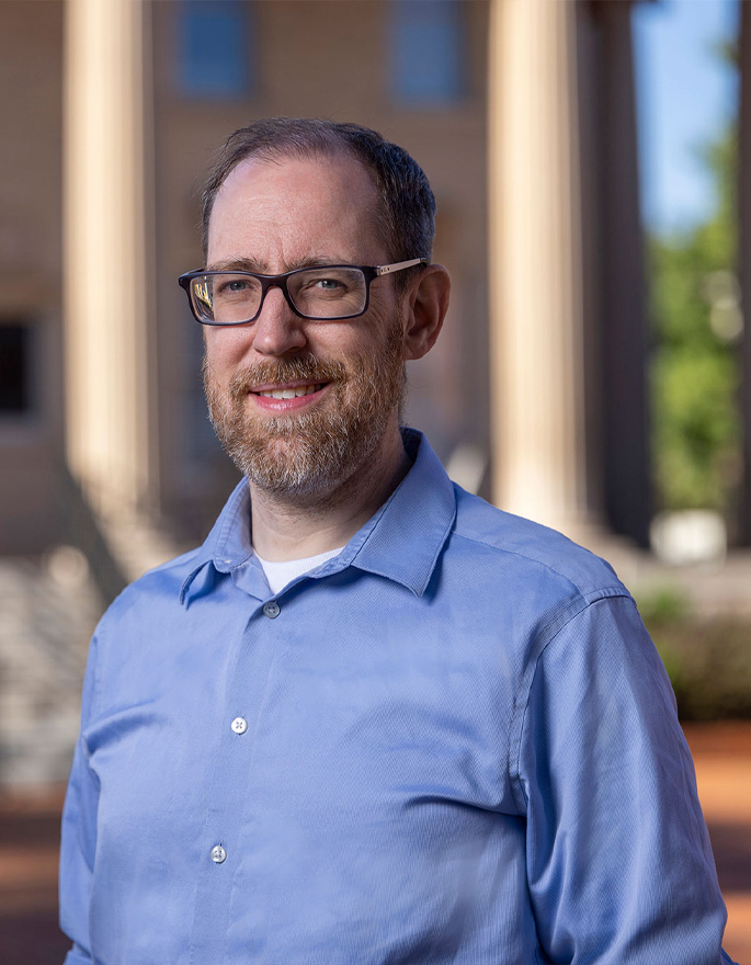 bioengineering second image- man in blue button down shirt with glasses standing outside