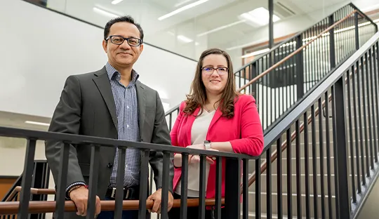 A man and woman, Hitesh Handa and Elizabeth Brisbois, pose on a stairway.