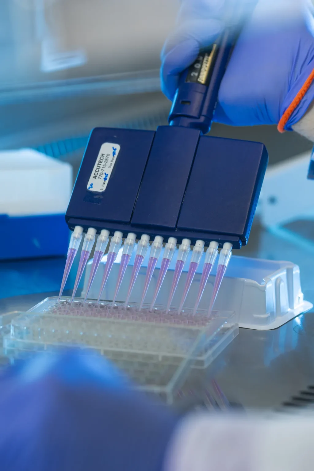 A closeup of medical equipment attached to tiny vials with pink fluid.