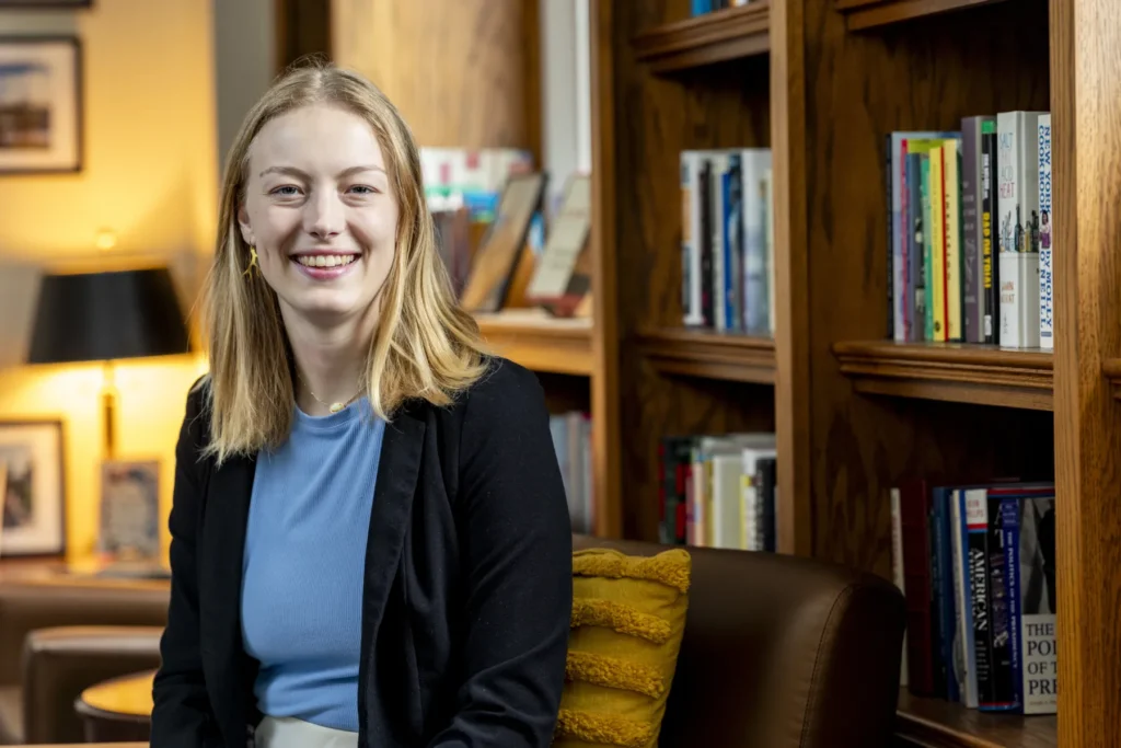 A young woman viewed from the waist up sitting in a cozy office.